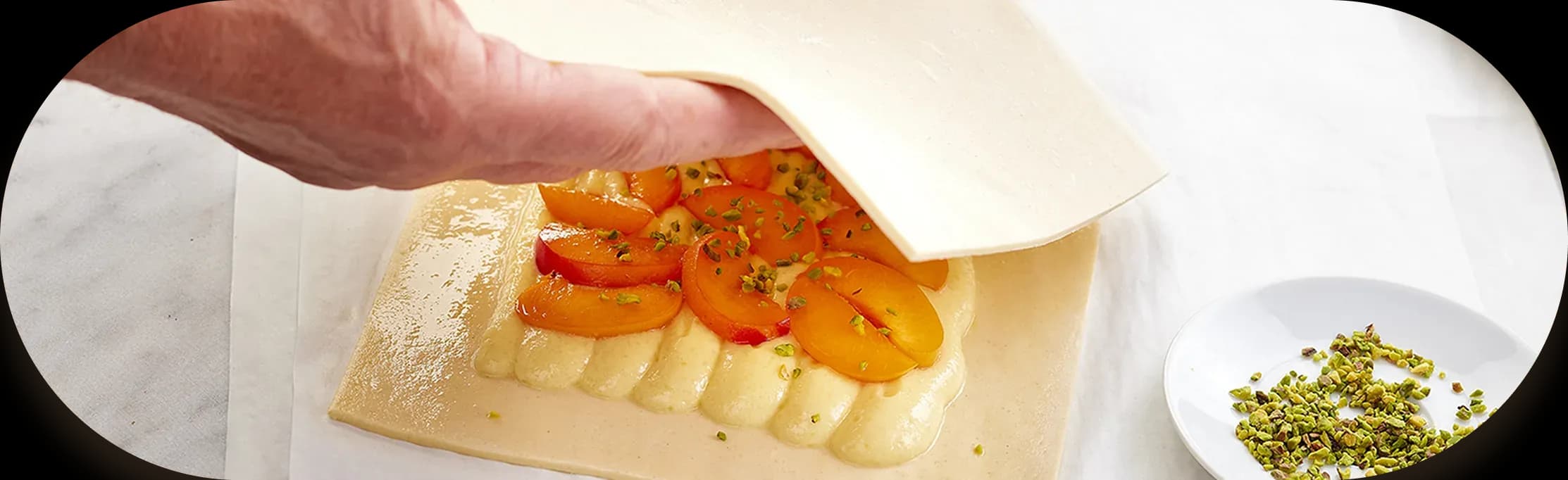 Puff pastry being folded over an apricot and pistachio filling