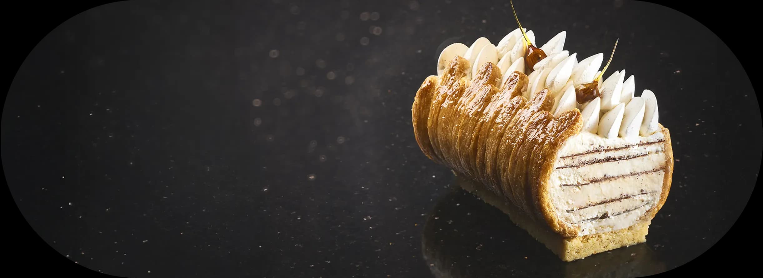 Choux pastry log topped with cream on a black background