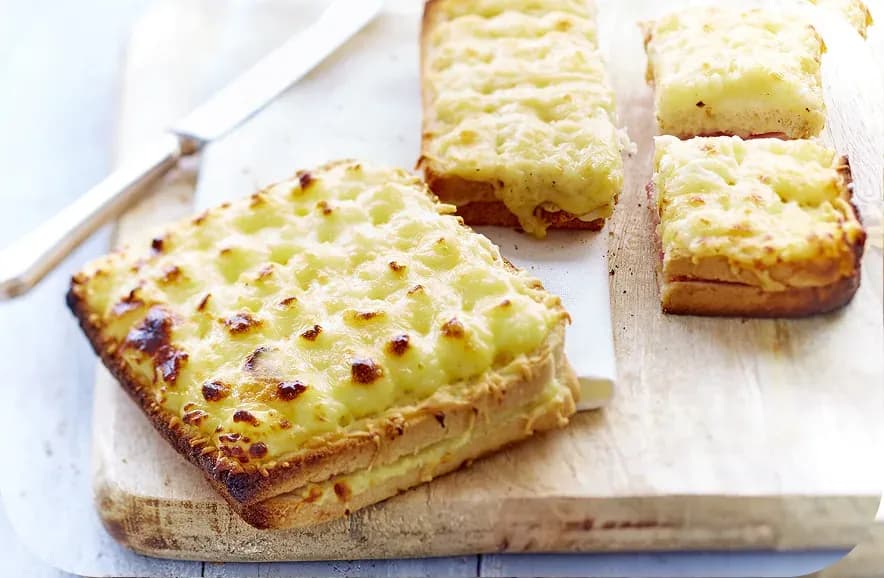 Cheese-topped toasts on a wooden board