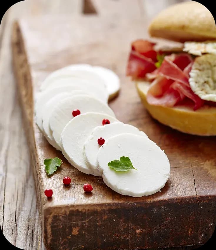 Sliced mozzarella and cured ham on a wooden board